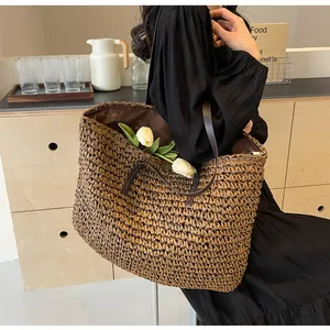 Close-up of a large dark brown straw tote bag showing woven texture and leather straps