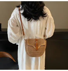 Détail d'un sac besace en paille avec bandoulière en cuir marron et boucle dorée