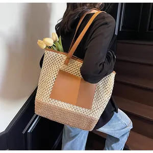 Dettaglio della borsa tote in paglia intrecciata con cuciture a contrasto e patch in pelle