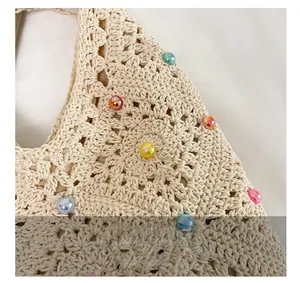 Close-up of beige crochet bag featuring colorful pearls and intricate hollow weave detail