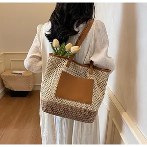 Dettaglio di una borsa tote in paglia intrecciata con inserti in pelle marrone e fiori