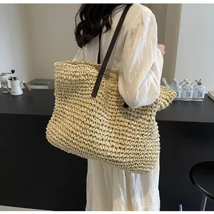 Detail of hand-woven straw tote bag showing clear texture and dark brown leather straps