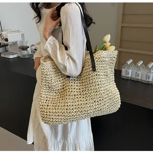 Detail of handwoven straw tote bag with brown leather shoulder straps and large capacity