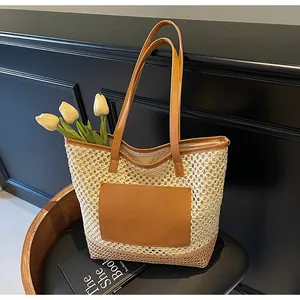 Dettaglio della borsa tote in paglia intrecciata con manici in pelle marrone e toppa decor