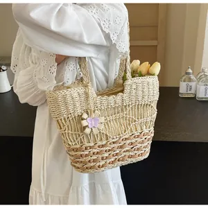 Dettaglio della borsa tote in paglia intrecciata con motivo a onde e fiore viola