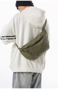 Detail of dark green canvas crossbody bag with multiple zippers and adjustable strap