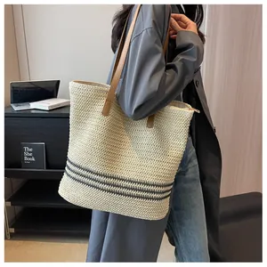 Détail du sac cabas en paille tressée avec bandoulière en cuir brun et fermeture éclair