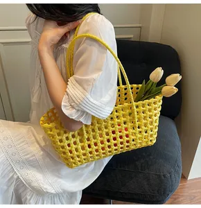 Detail of a bright yellow woven tote bag with sturdy mesh design held by a model