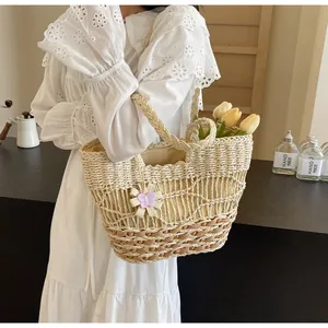 Dettaglio borsa tote in paglia intrecciata con motivo a onde e ciondolo a farfalla viola