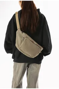 Rear view of model wearing a large khaki canvas crossbody bag with wide shoulder strap
