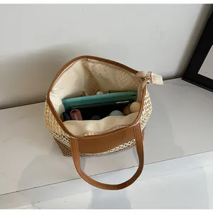 Vista dettagliata dell'interno spazioso della borsa intrecciata con cerniera e oggetti
