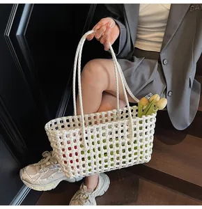 Close-up of white woven beach bag featuring intricate hollow-out texture and long handles