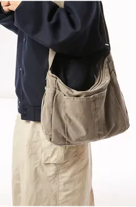 Detailed side view of dark khaki canvas messenger bag showing multiple exterior pockets