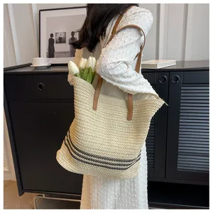 Détail d'un sac de plage tissé beige avec rayures noires et fines anses en cuir brun
