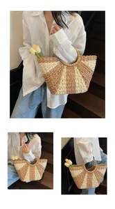 Detail of hand-woven straw tote with radial stripes and ring handles on a model