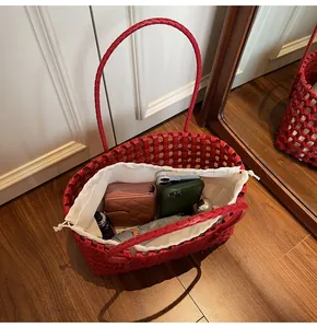 Detail of red woven leather tote bag showing interior storage capacity and white pouch