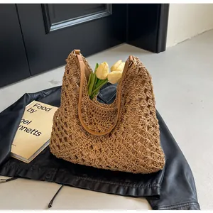 Detail of hollow woven straw tote with brown leather handles and decorative tulips