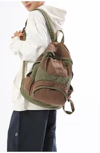 Side view of a vintage canvas backpack in olive green and brown on a model