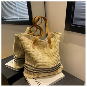 Détail du sac cabas tissé avec rayures bleu marine et poignées en cuir marron