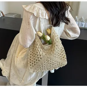 Detail of hollow-out hand-woven beige tote with brown leather strap and flowers