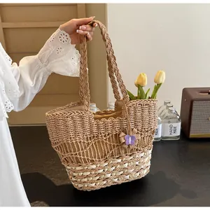 Dettaglio borsa in paglia intrecciata a mano con bordo ondulato e farfalla viola