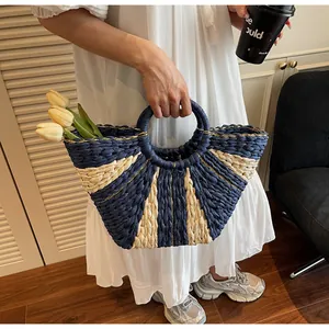 Detail of handwoven straw tote with navy stripes, gold stitching and floral decor