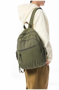 Dettaglio dello zaino in tela verde militare con tasche multiple e tiranti con coulisse