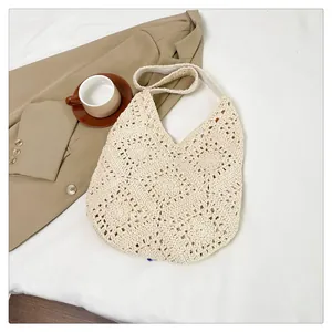 Close-up of handmade crochet granny square pattern on a beige bohemian beach tote bag