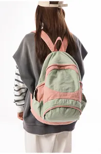 Rear view of a model wearing the large color-block canvas backpack in green and pink