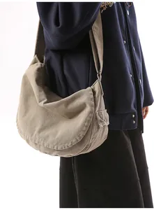 Detail view of khaki canvas messenger bag with wide shoulder strap and side snap pocket