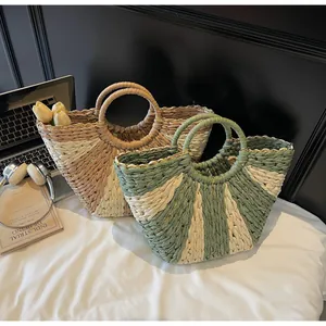 Close-up of woven straw bags in khaki and sage green with round handles and gold trim