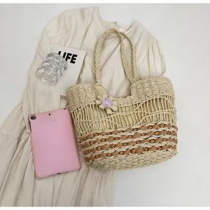 Dettaglio della borsa tote in paglia intrecciata con fiocco viola e motivo beige