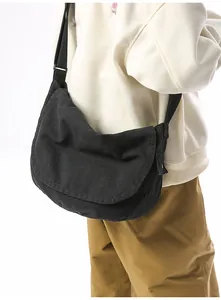 Side view of black canvas messenger bag on model showing large capacity and adjustable strap