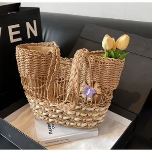 Dettaglio della borsa tote in paglia intrecciata con ciondolo a farfalla viola in regalo