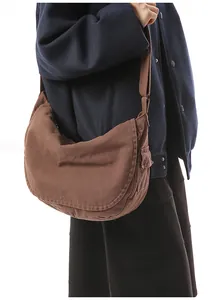 Close-up of brown canvas messenger bag with adjustable strap and side pocket detail