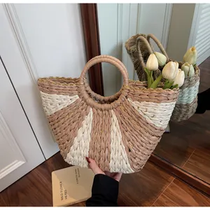 Detail of hand-woven straw tote with golden thread accents and circular handles