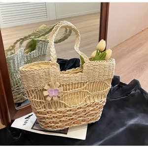 Dettaglio della borsa in paglia intrecciata con motivo a onde e ciondolo a fiore viola