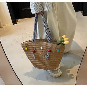 Close-up of a large straw tote bag with colorful bead accents and striped fabric handles