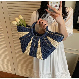 Close-up of handmade woven straw bag with navy stripes and metallic gold thread detail