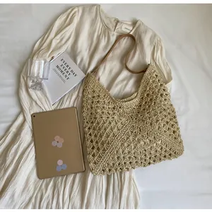Flat lay of a beige woven hobo bag with a brown leather strap on a stylish white dress