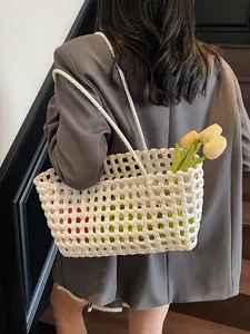 White woven hollow beach bag shoulder tote shown on model in a modern indoor setting