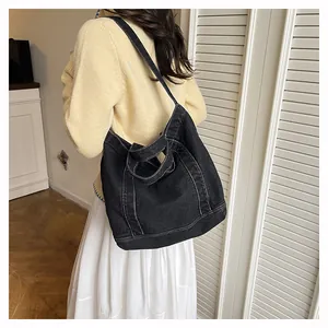 Detail of black denim tote bag with white contrast stitching and dual carry straps