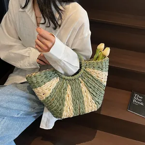 Close-up of green and beige woven straw handbag with radial stripe pattern in vacation setting