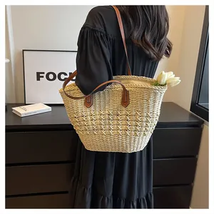 Detail of hand-woven straw tote bag featuring brown leather handles and spacious interior