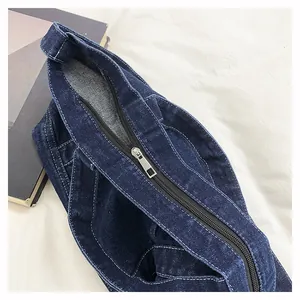 Detail of dark blue denim tote bag texture and sturdy silver metal zipper closure