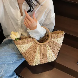Detail of a half-moon woven straw bag with two-tone stripes and circular handles