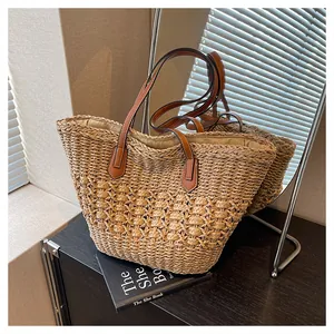 Detail of woven straw tote bag with brown leather handles and textured knit pattern