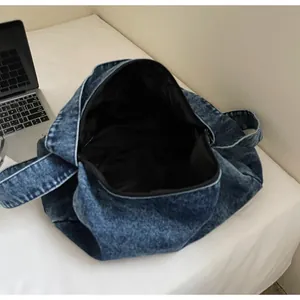 Detailed interior of large denim tote bag with black lining next to a laptop