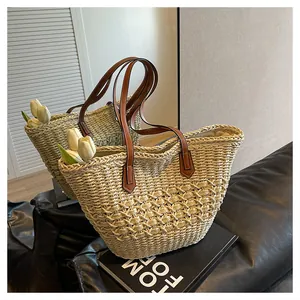 Close-up of woven straw tote bag with brown leather handles and white tulip flowers