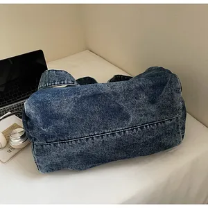 Macro view of washed denim crossbody bag featuring soft texture and wide shoulder strap